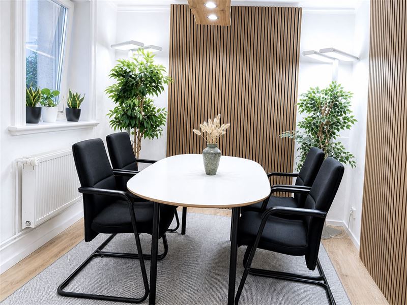 Besprechungsraum mit ovalem Tisch, Ledersesseln und Holzlamellen