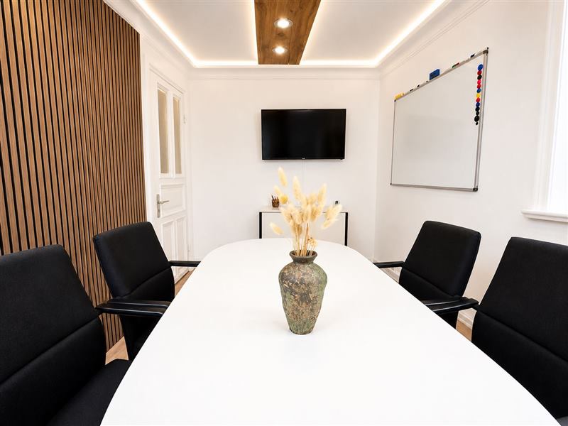 Meetingraum mit weißem Tisch und Bildschirm